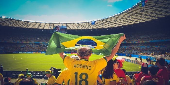 Ein brasilianischer Fußball Fan hält eine Flagge in die Höhe