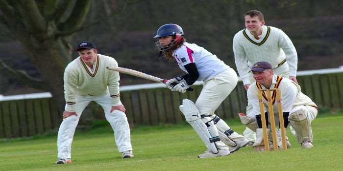 Vier Cricket Spieler stehen konzentriert auf dem Rasen