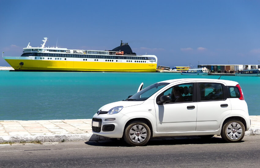 Ein Auto parkt am Straßenrand und im Hintergrund das Meer mit einem Kreuzfahrtschiff.