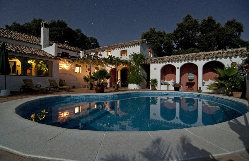 Der Hinterhof einer Villa mit einem steinumrandeten Swimmingpool.